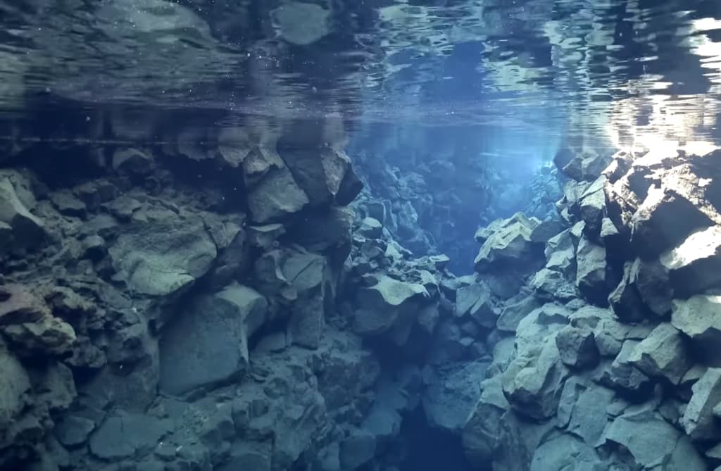 Une vue sous-marine tranquille montre des rochers sous une surface d'eau vitreuse