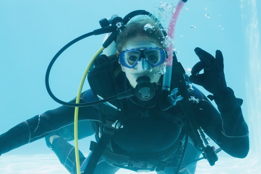 La fille dans l'équipement du plongeur sous l'eau