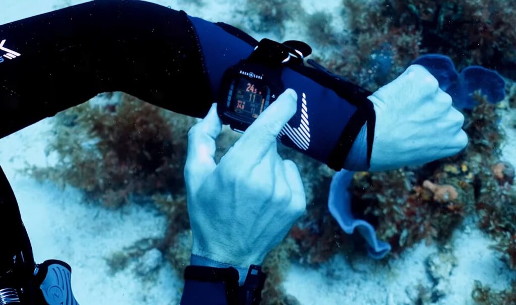 Plongeur vérifiant sa montre de plongée sous l'eau près d'un récif